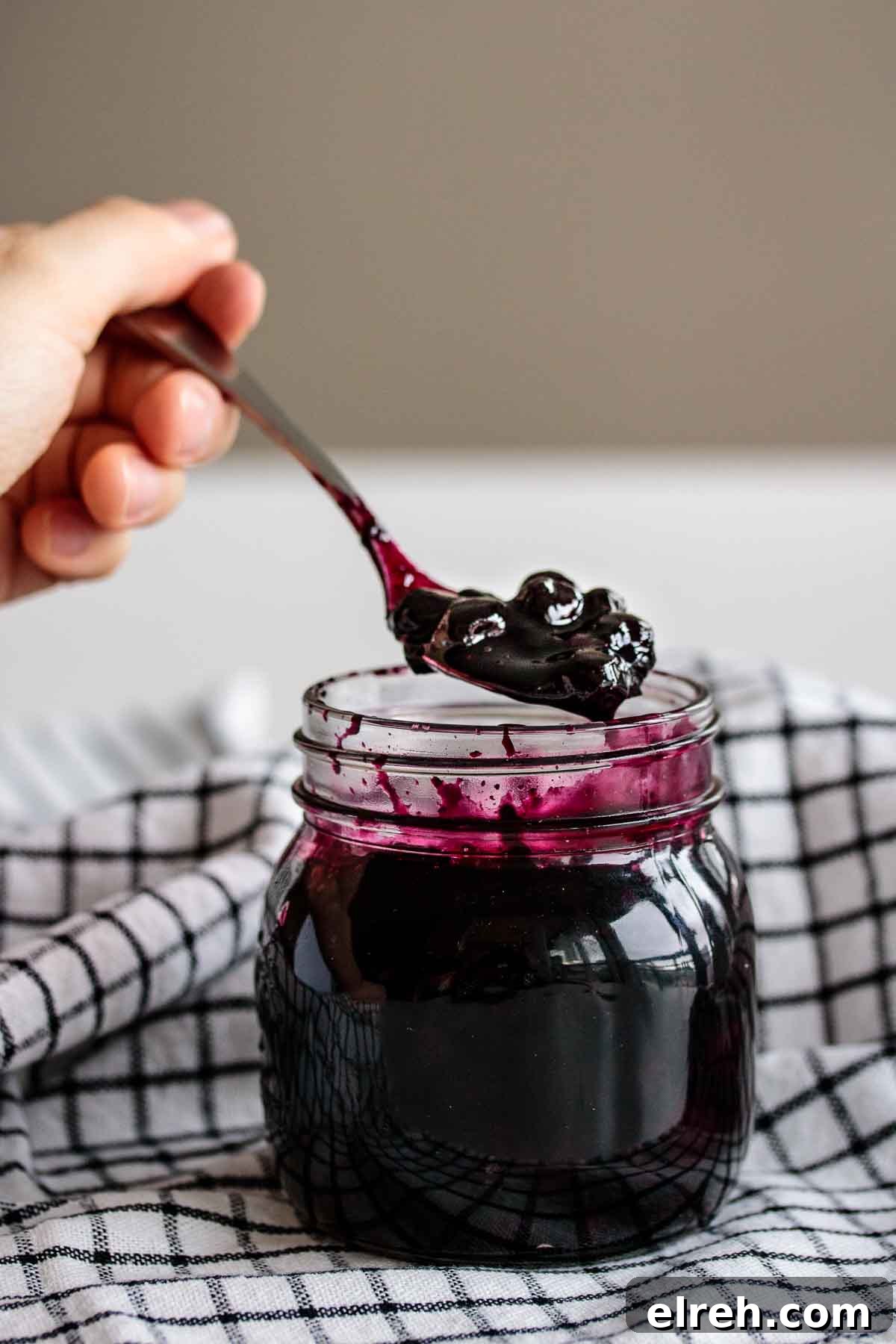 A hand holding a spoon full of compote