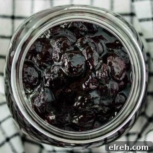 Close up of a jar of blueberry compote over a kitchen towel