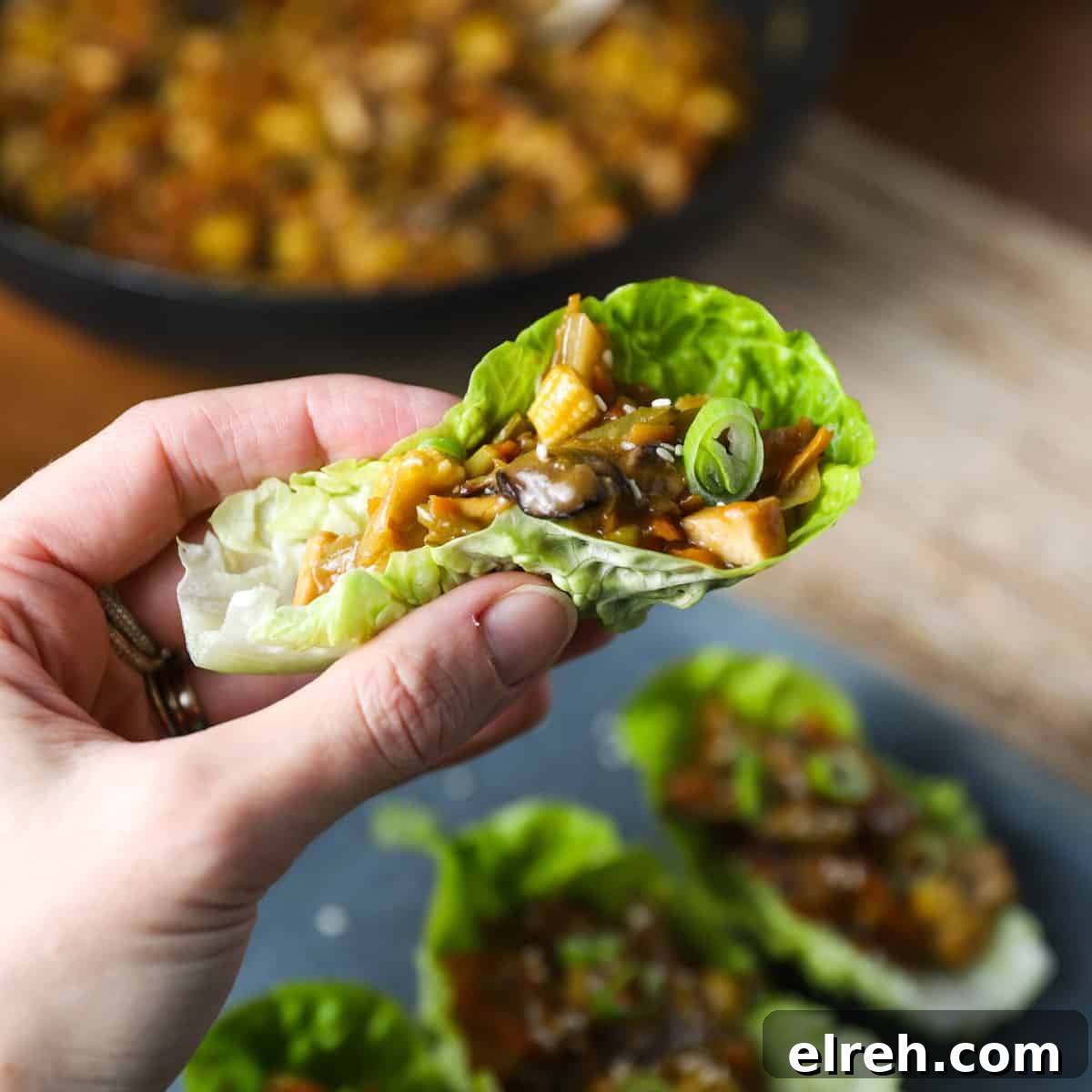 Vegan San Choy Bau Lettuce Cups 12 Photo of a hand holding a lettuce leaf filled with vegan san choy bau filling.