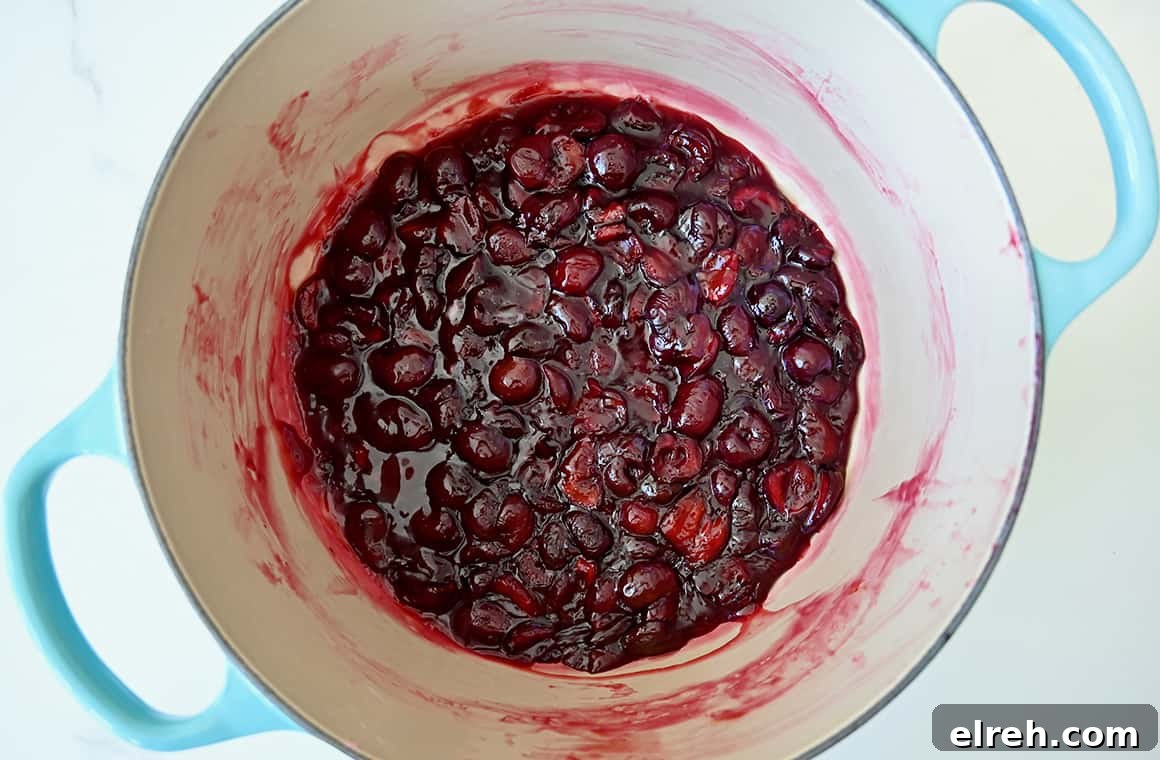 A top-down view of fresh cherry pie filling in a large saucepan