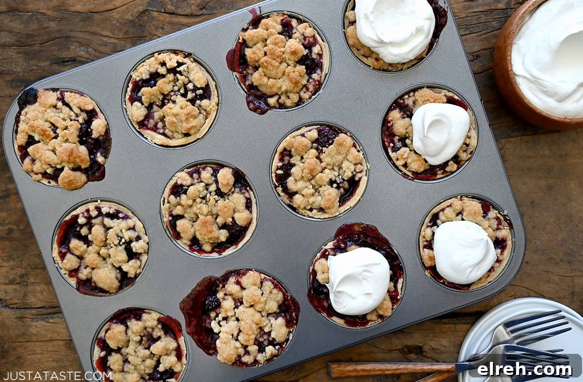 Homemade muffin tin Mini Cherry Pies topped with streusel and whipped cream