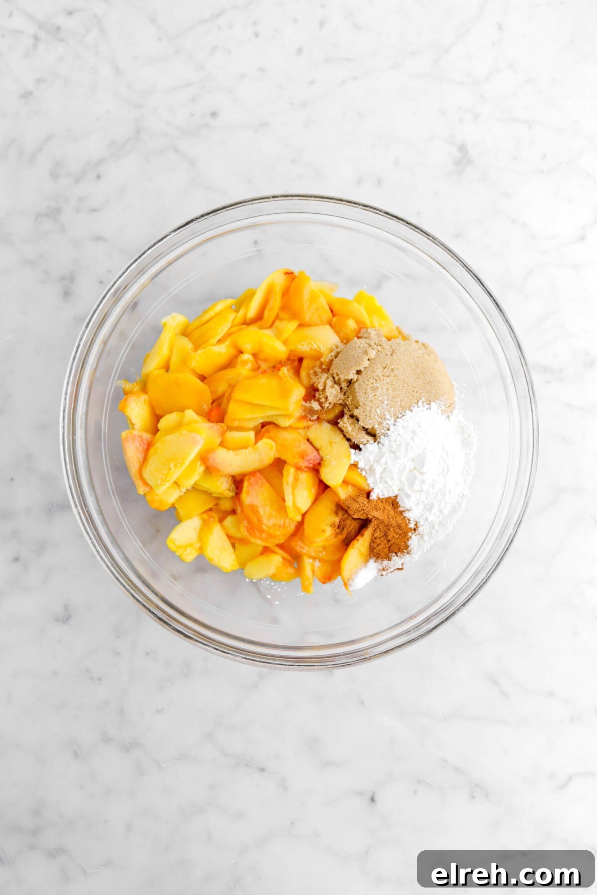 Peach Cobbler Crisp with Brown Sugar and Cinnamon 12 sliced peaches, brown sugar, corn starch, and cinnamon in glass bowl.