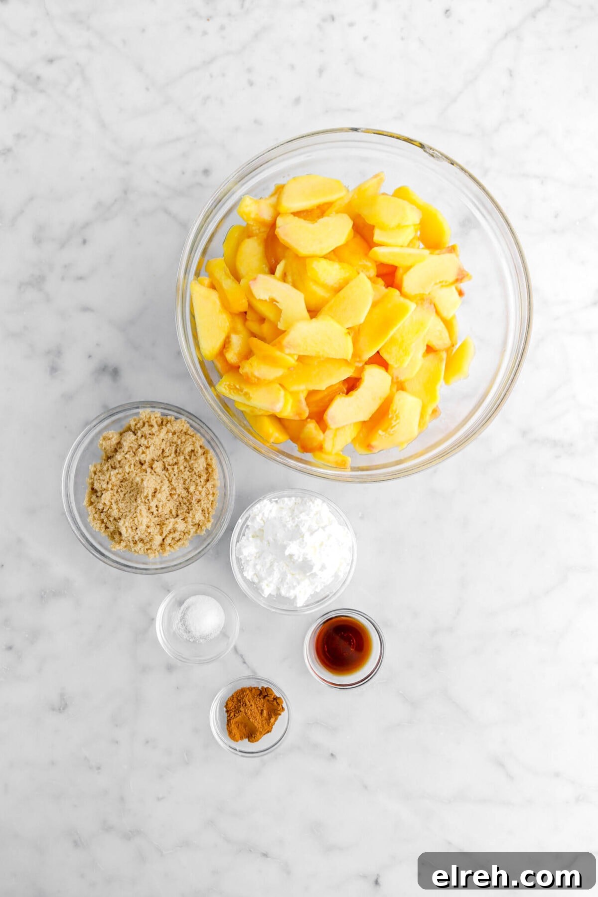 Peach Cobbler Crisp with Brown Sugar and Cinnamon 8 slices peaches, brown sugar, corn starch, salt, vanilla, and cinnamon on marble surface.