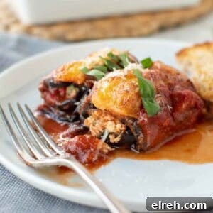 Close up of two eggplant involtini on a white plate.