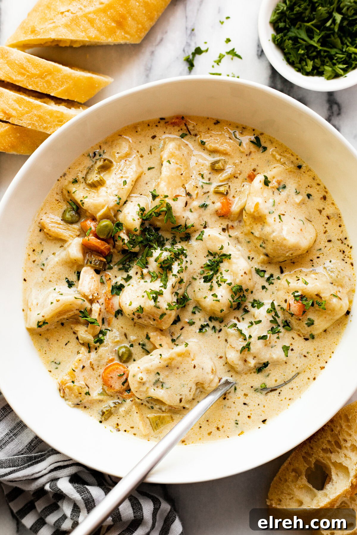 White bowl filled with homemade chicken dumpling soup garnished with parsley.