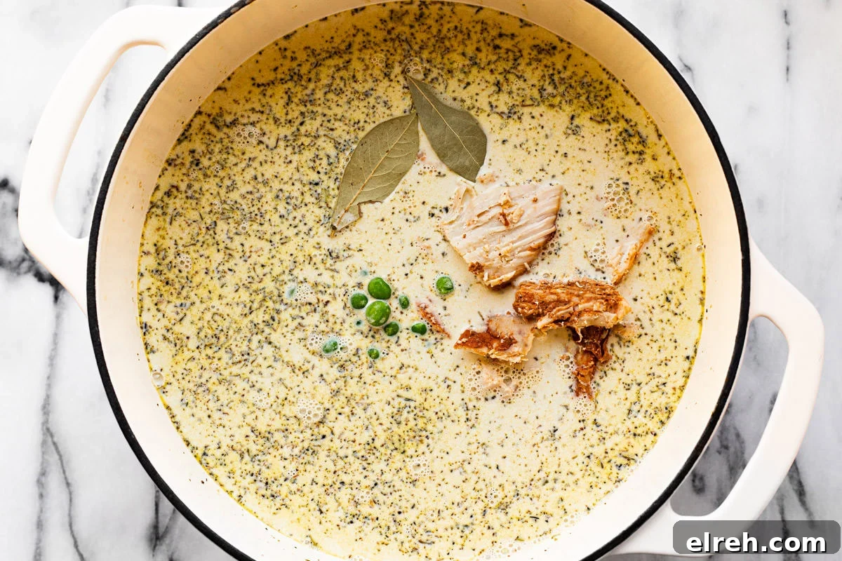 Ingredients to make the broth of chicken and dumpling soup in a white pot.