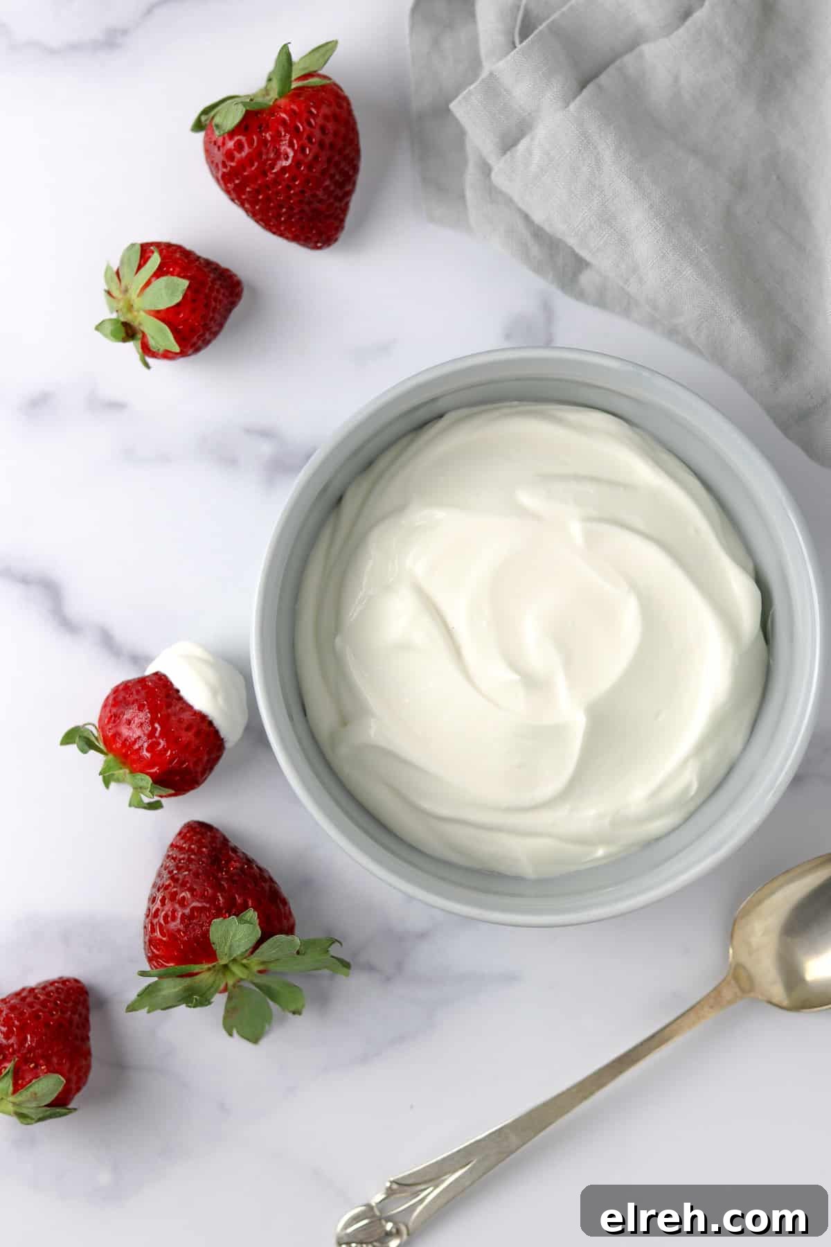 Whipped Vanilla Cream Skyr in a bowl next to strawberries and a spoon.