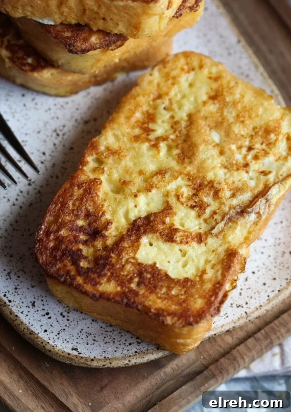 A Slice of Super Fluffy French Toast on a Speckled Plate