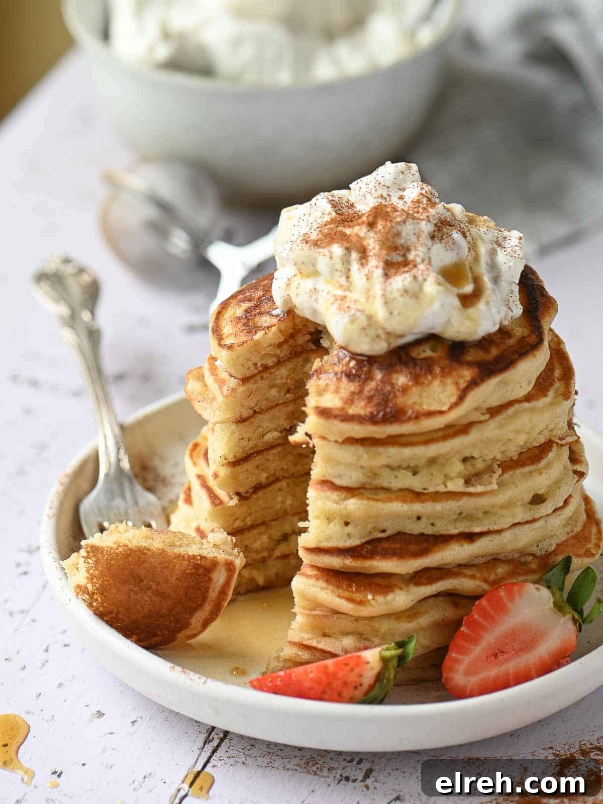 Fluffy Sweet Cream Cinnamon Pancakes Recipe 9 A stack of cinnamon pancakes cut with a piece on a fork to the left.