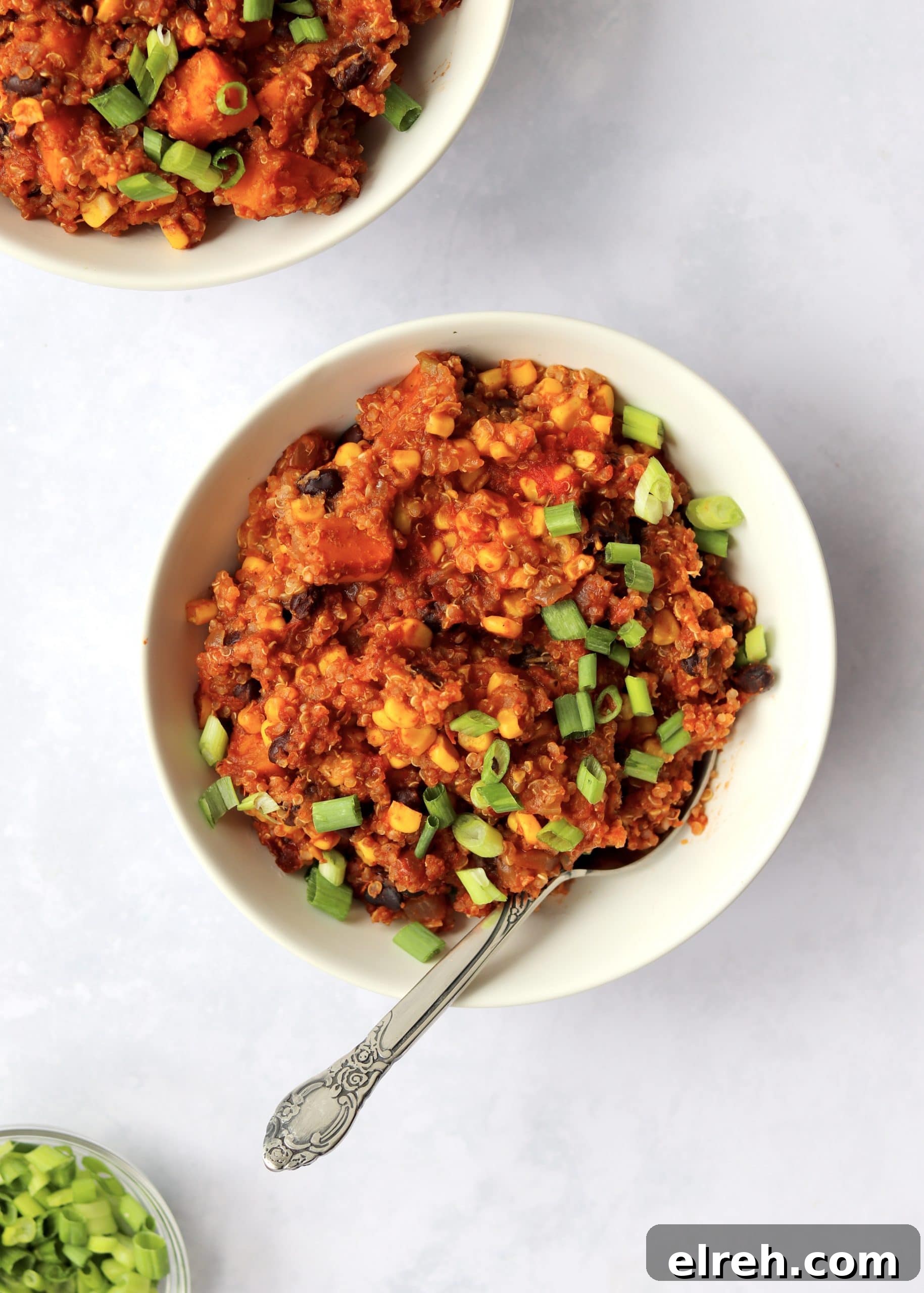 Vegan Slow Cooker Mexican Quinoa Recipe 5 Two bowls of Mexican quinoa with a spoon and green onions