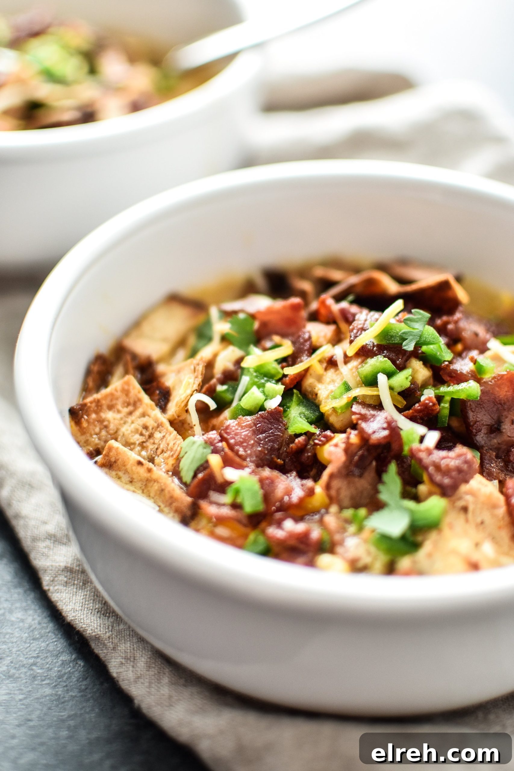 A bowl of jalapeno popper chicken soup from the side with toppings.