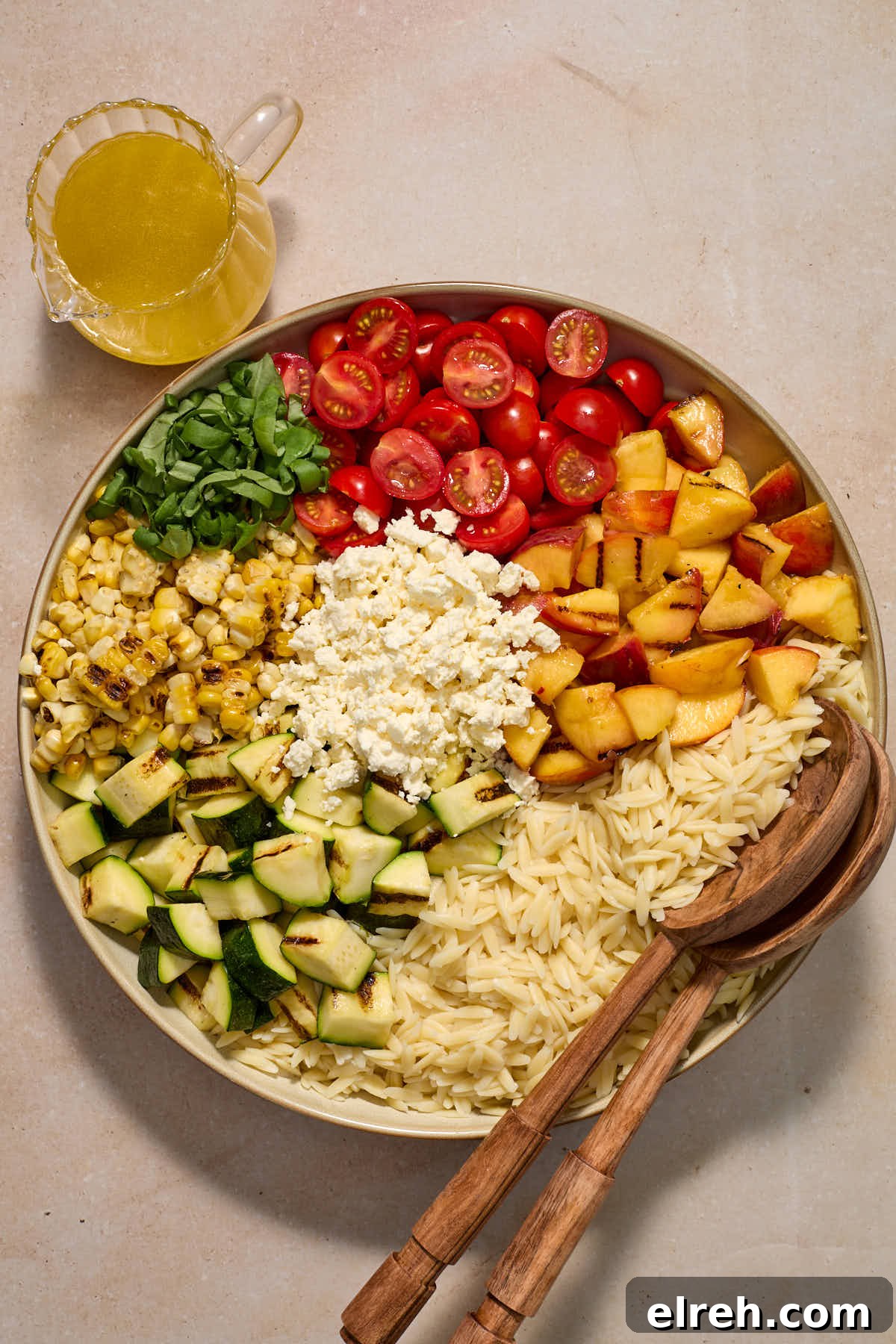 Grilled Vegetable Orzo Salad with Summer Peaches 9 All of the salad ingredients sectioned in a large bowl with dressing on the side.