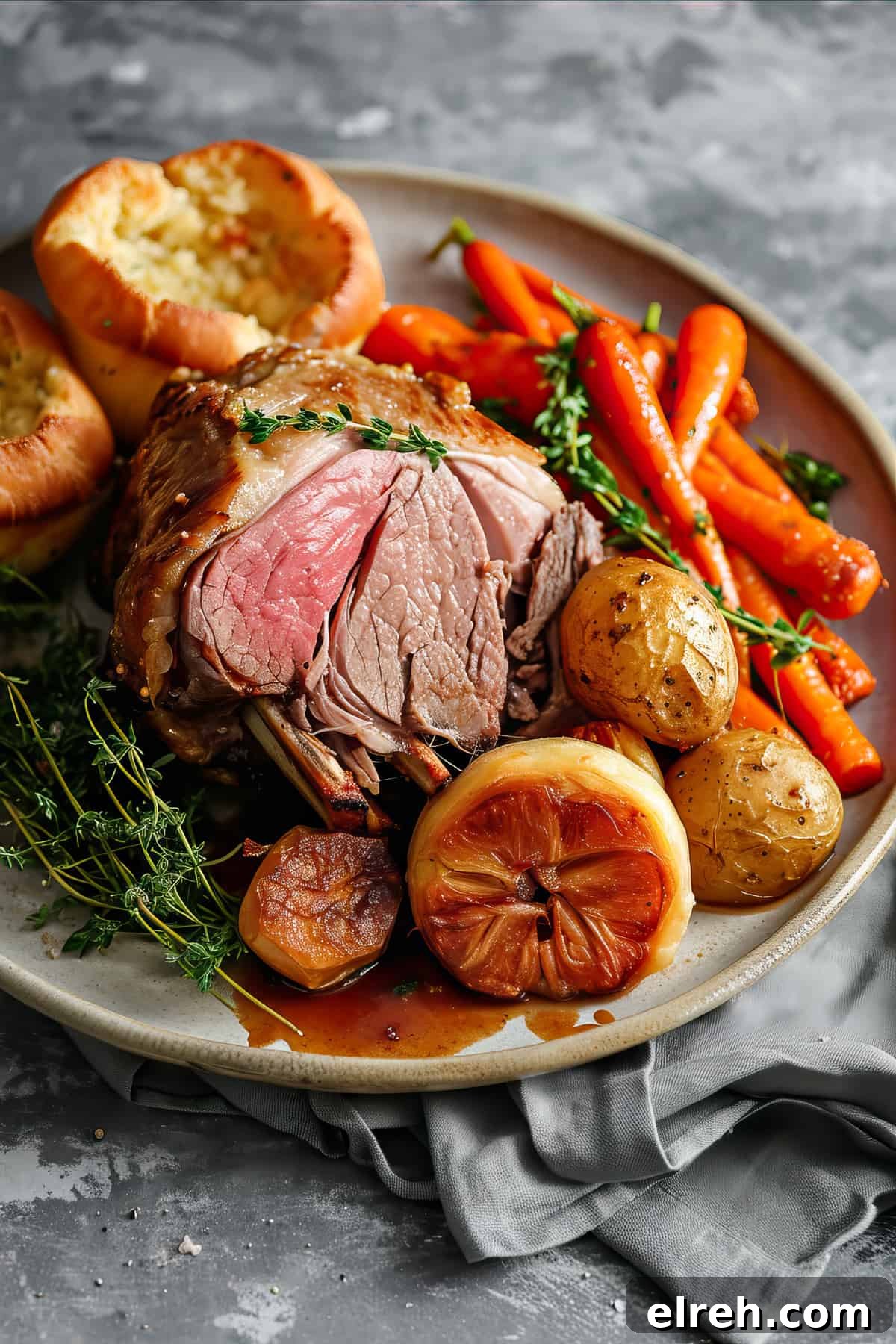 Roast leg of lamb with herbs, roast potatoes and glazed carrots on a plate.