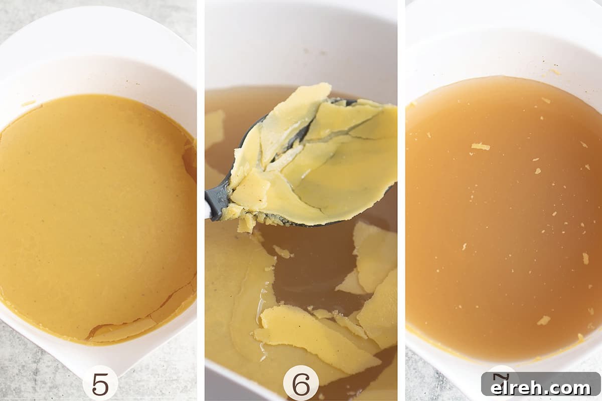 Turkey broth in a white bowl with fat being removed using a slotted spoon.