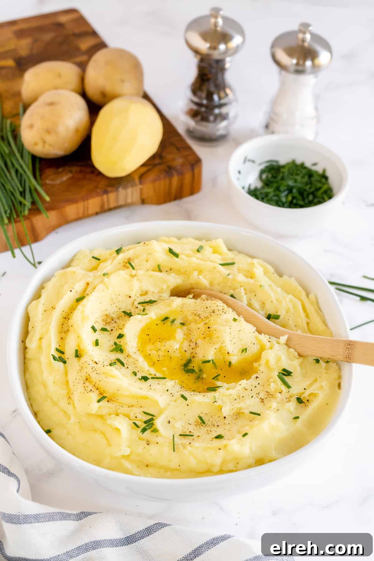 Creamy Buttermilk Mashed Potatoes Recipe 3 A wooden spoon in a bowl of mashed potatoes.