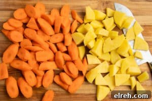 Chopped carrots and potatoes on a cutting board.