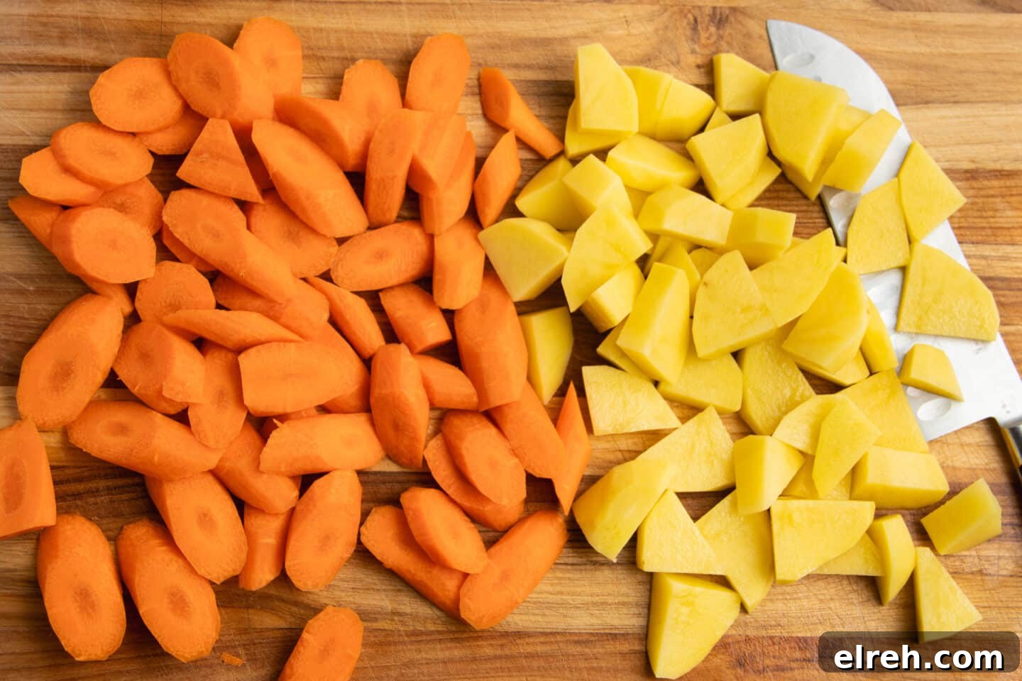 Chopped carrots and potatoes on a cutting board.
