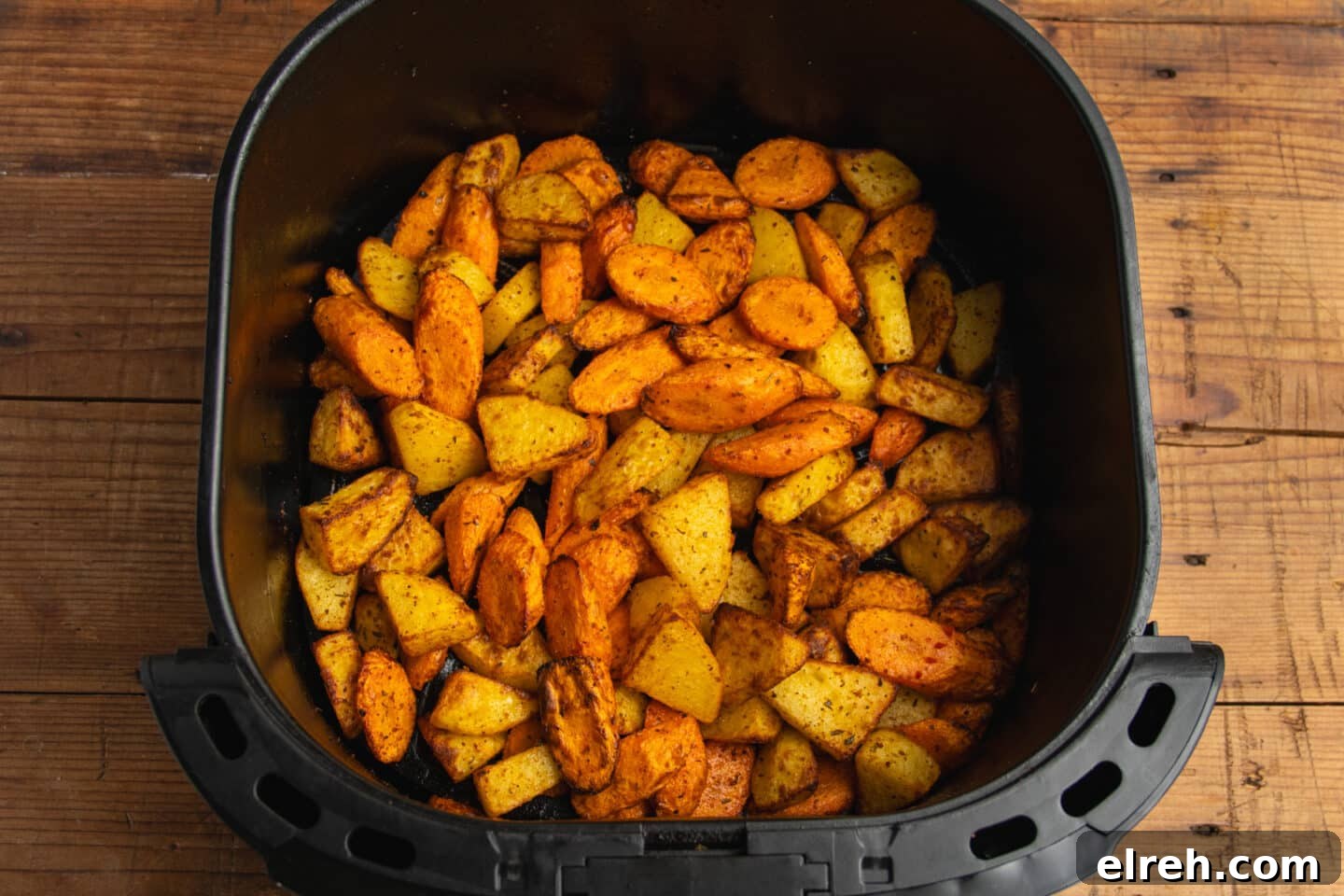 Cooked carrots and potatoes in the air fryer basket.
