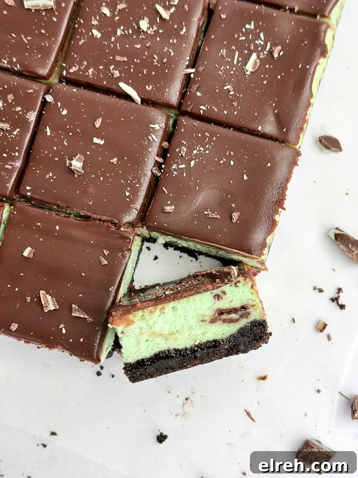 a close up of a square of chocolate mint cheesecake turned diagonal to see the layers.