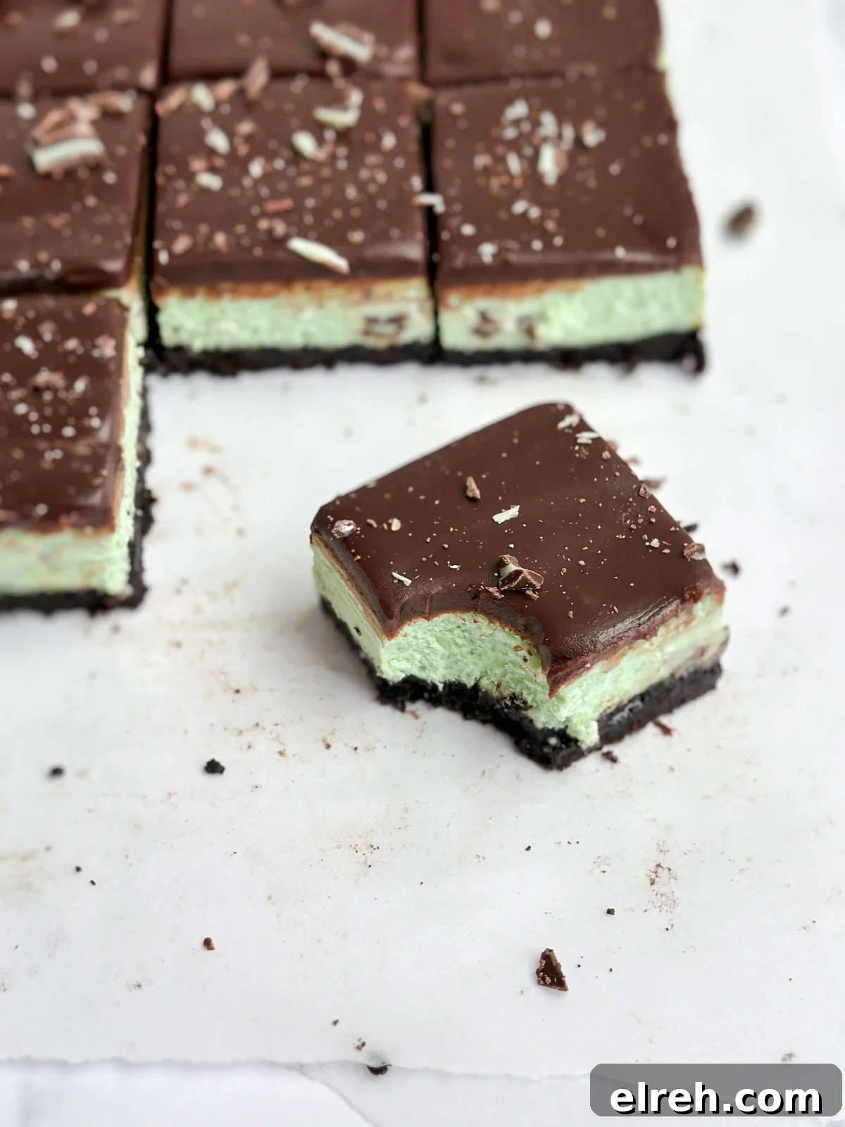 a single square of chocolate mint cheesecake with a bite taken out.