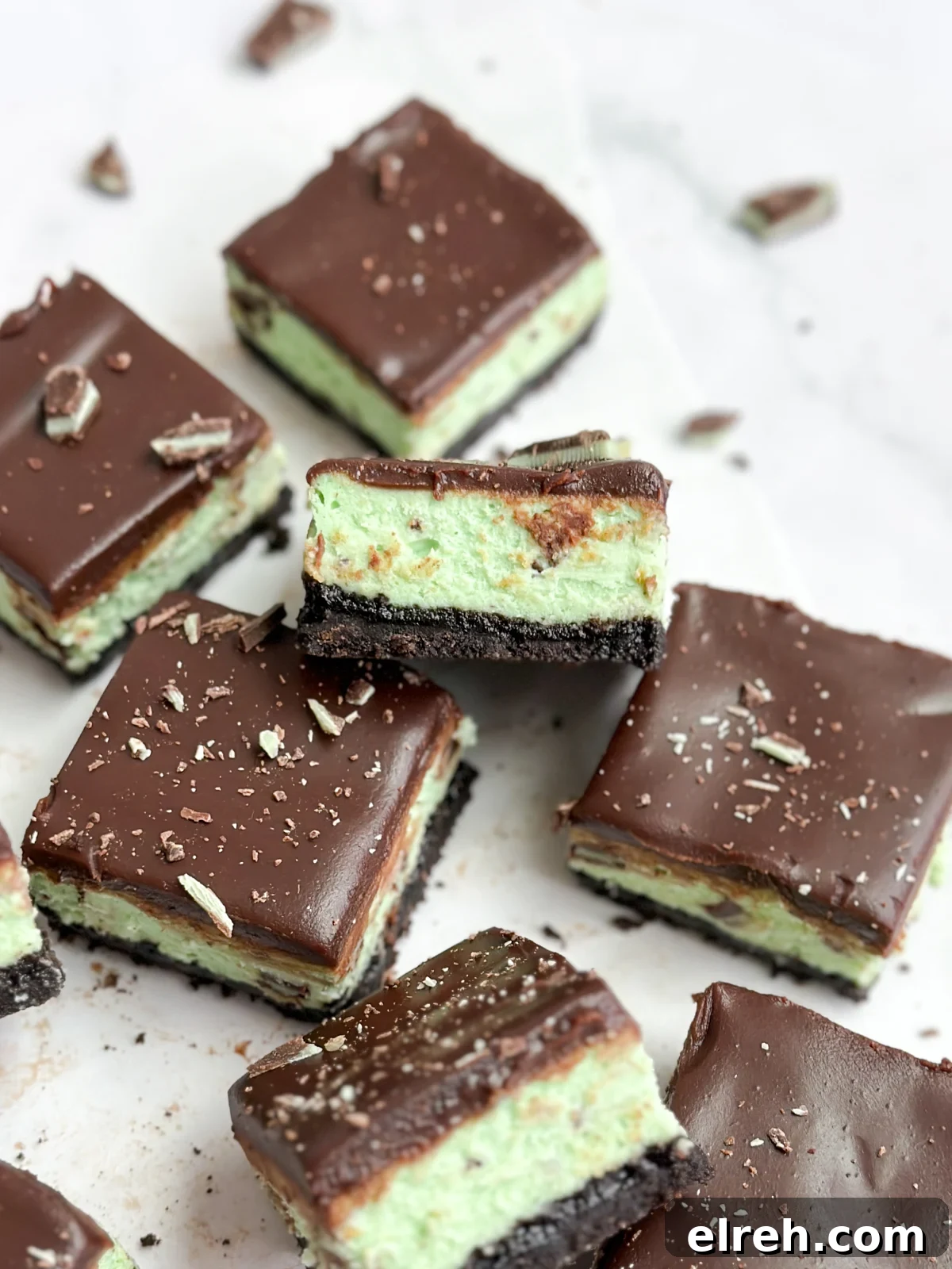 a bunch of chocolate mint cheesecake bars stacked and scattered.