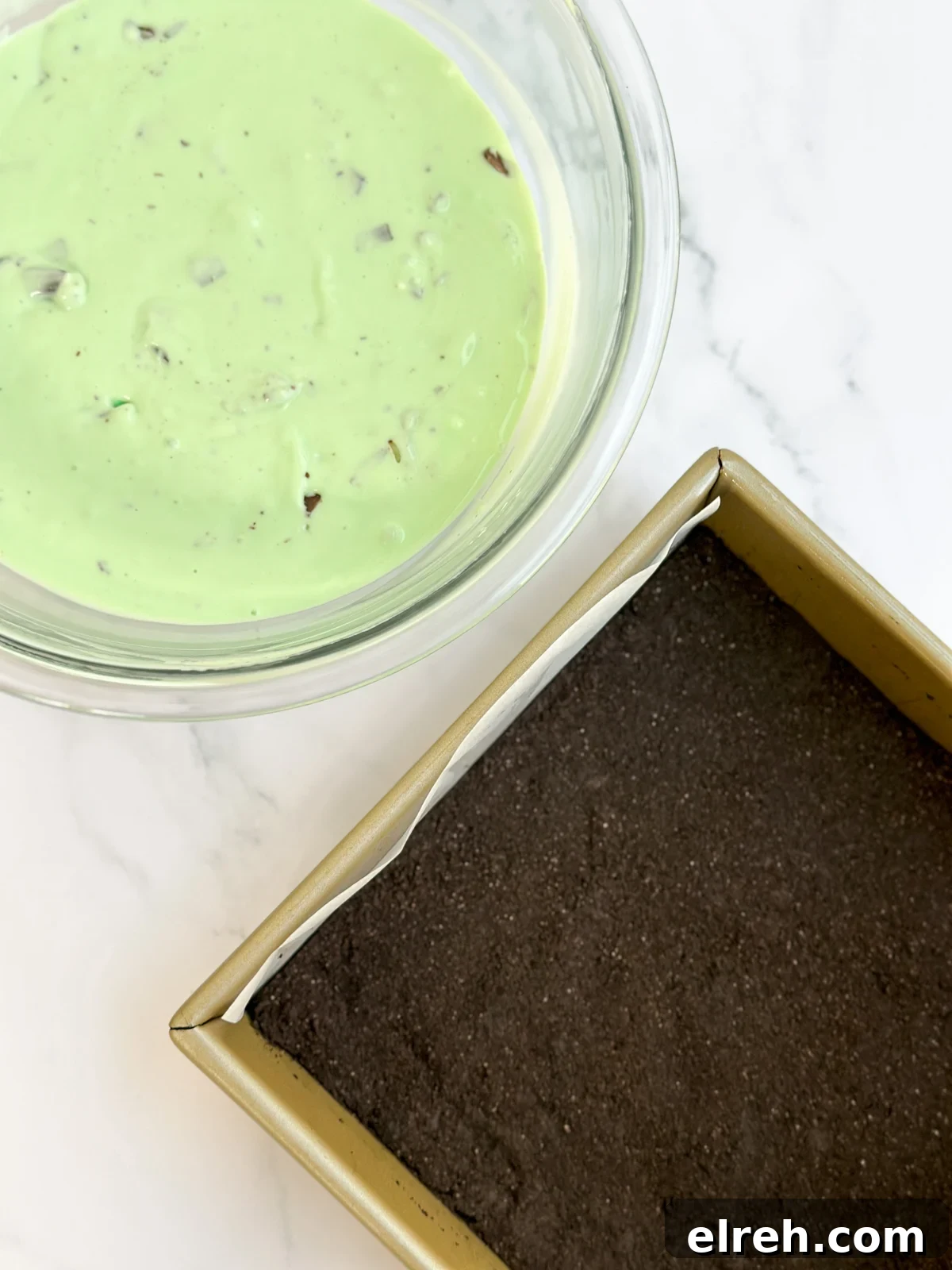 a bowl of cheesecake batter and the crust in the baking pan.