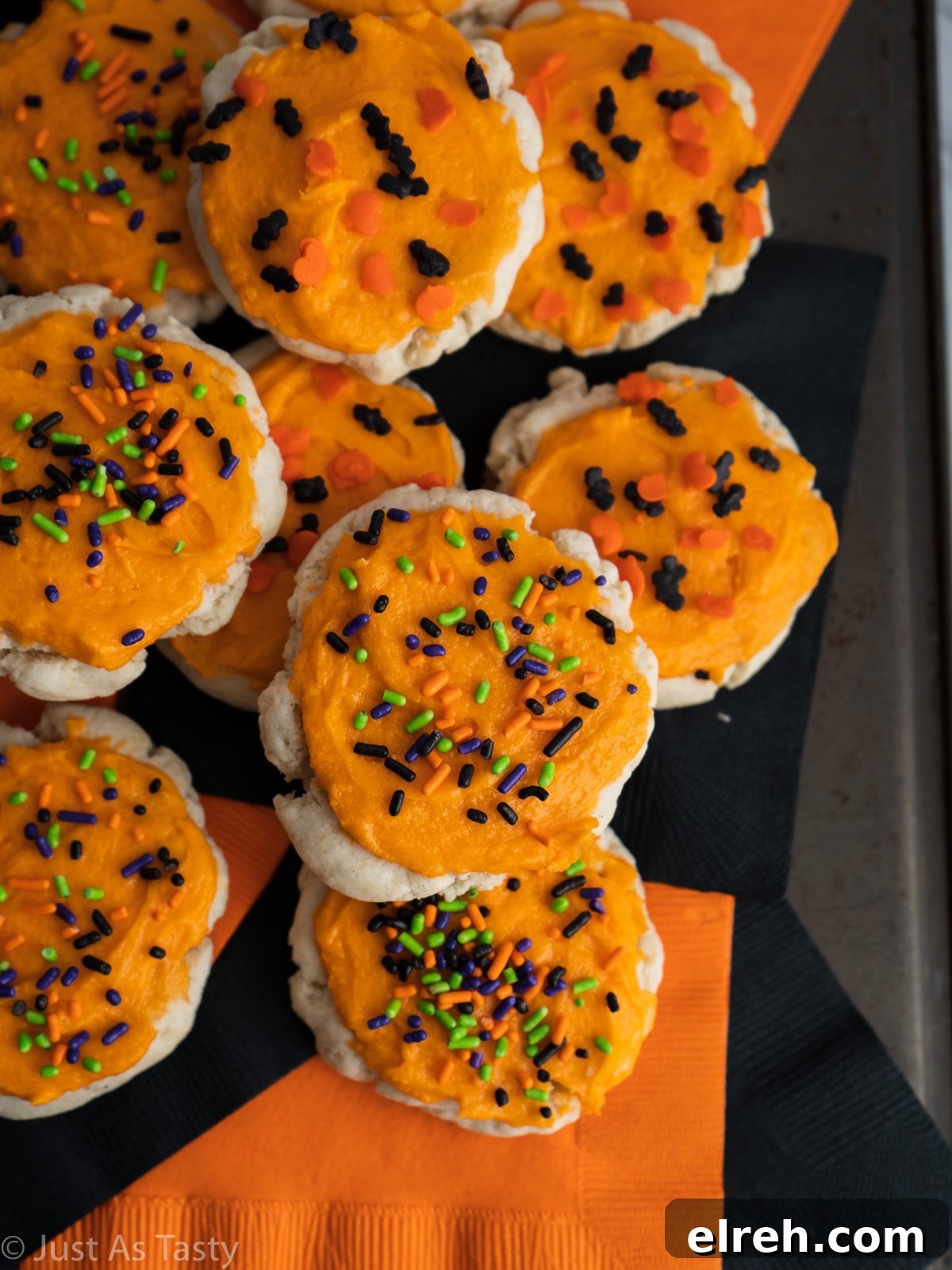 Round sugar cookies topped with orange buttercream frosting and Halloween sprinkles.