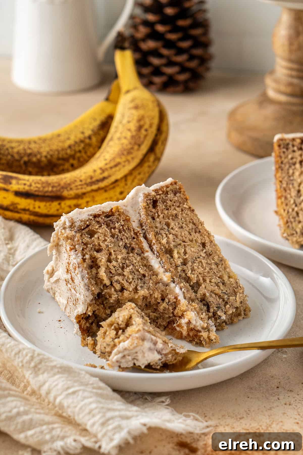 A slice of vegan banana cake on a plate with a fork taking a bite.