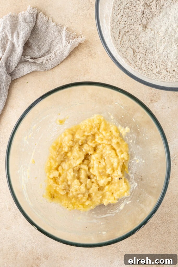 A bowl of mashed banana and another with the dry ingredients.