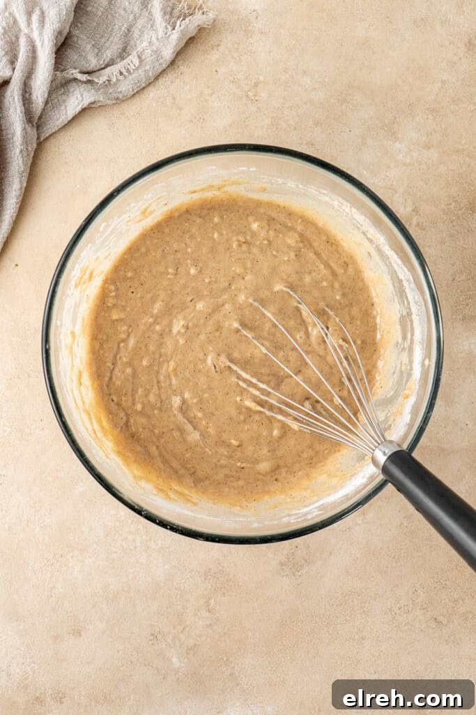 The cake batter and a whisk in a glass bowl.
