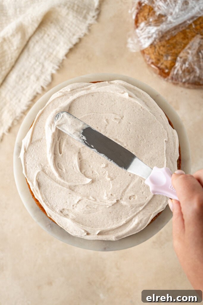 Spreading buttercream onto the cake with a cake knife.
