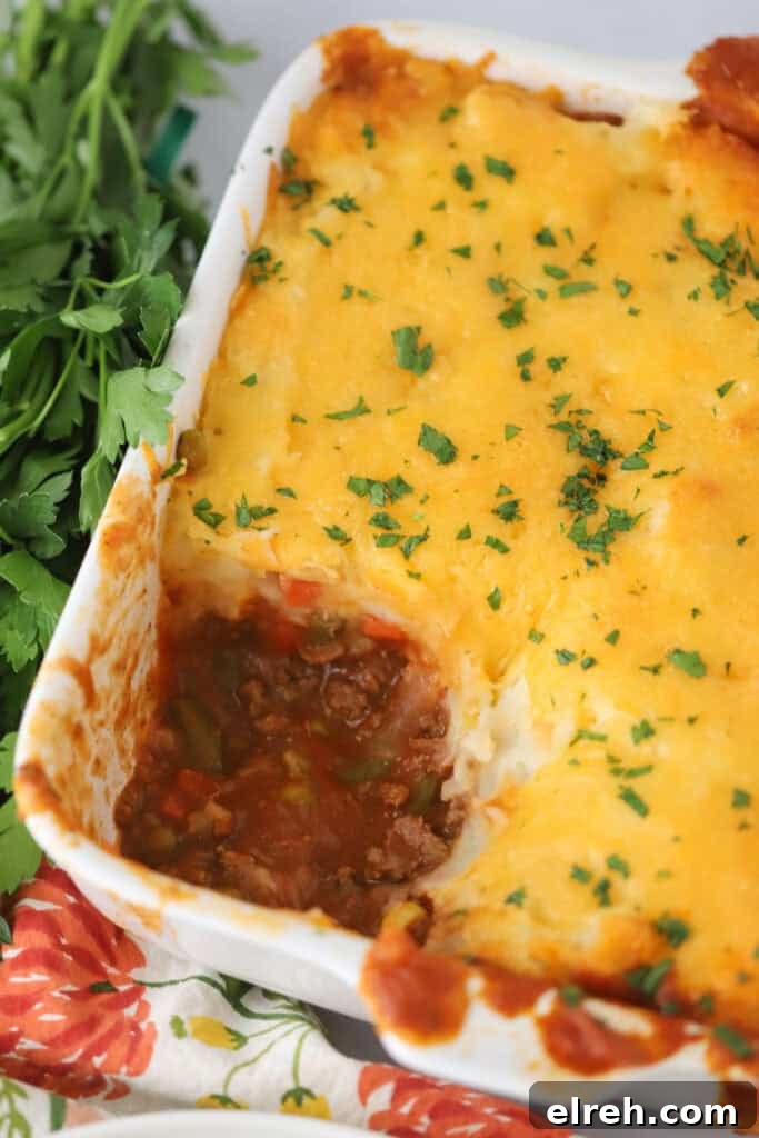 Shepherd's Pie Recipe with Savory Lamb and Mashed Potatoes 6 A large baking dish full of shepherd's pie with a large portion removed.