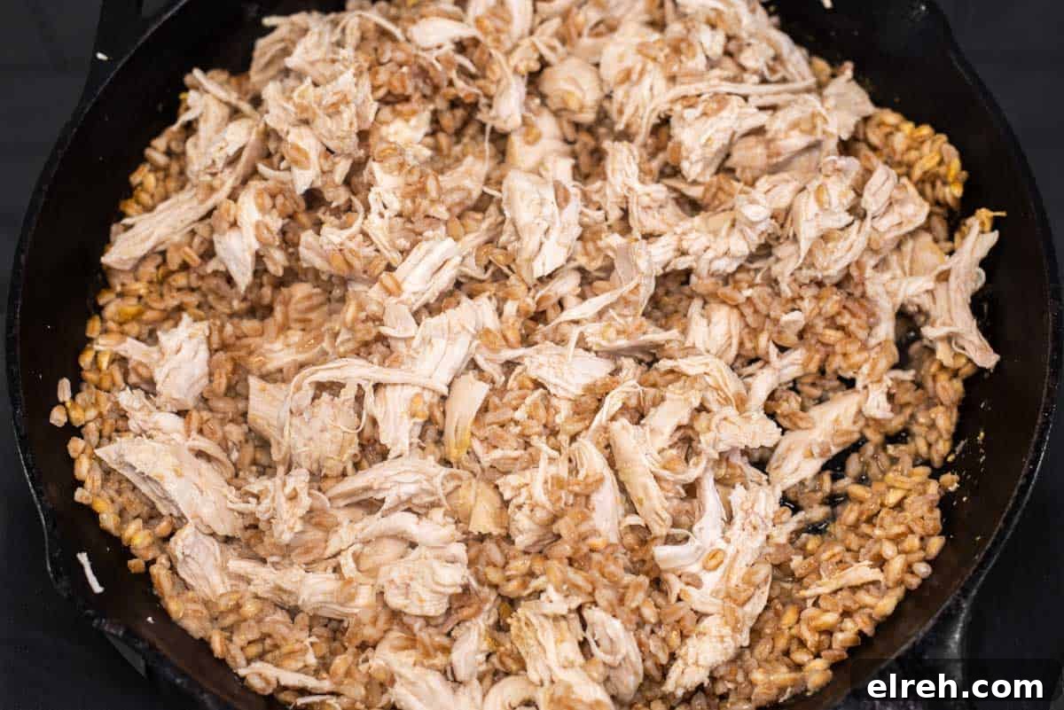 One-Pan Cheesy Chicken Enchilada Skillet 5 Chicken shredded with farro in skillet.