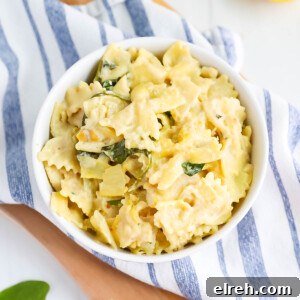 Creamy white sauce pasta with spinach in a white bowl.