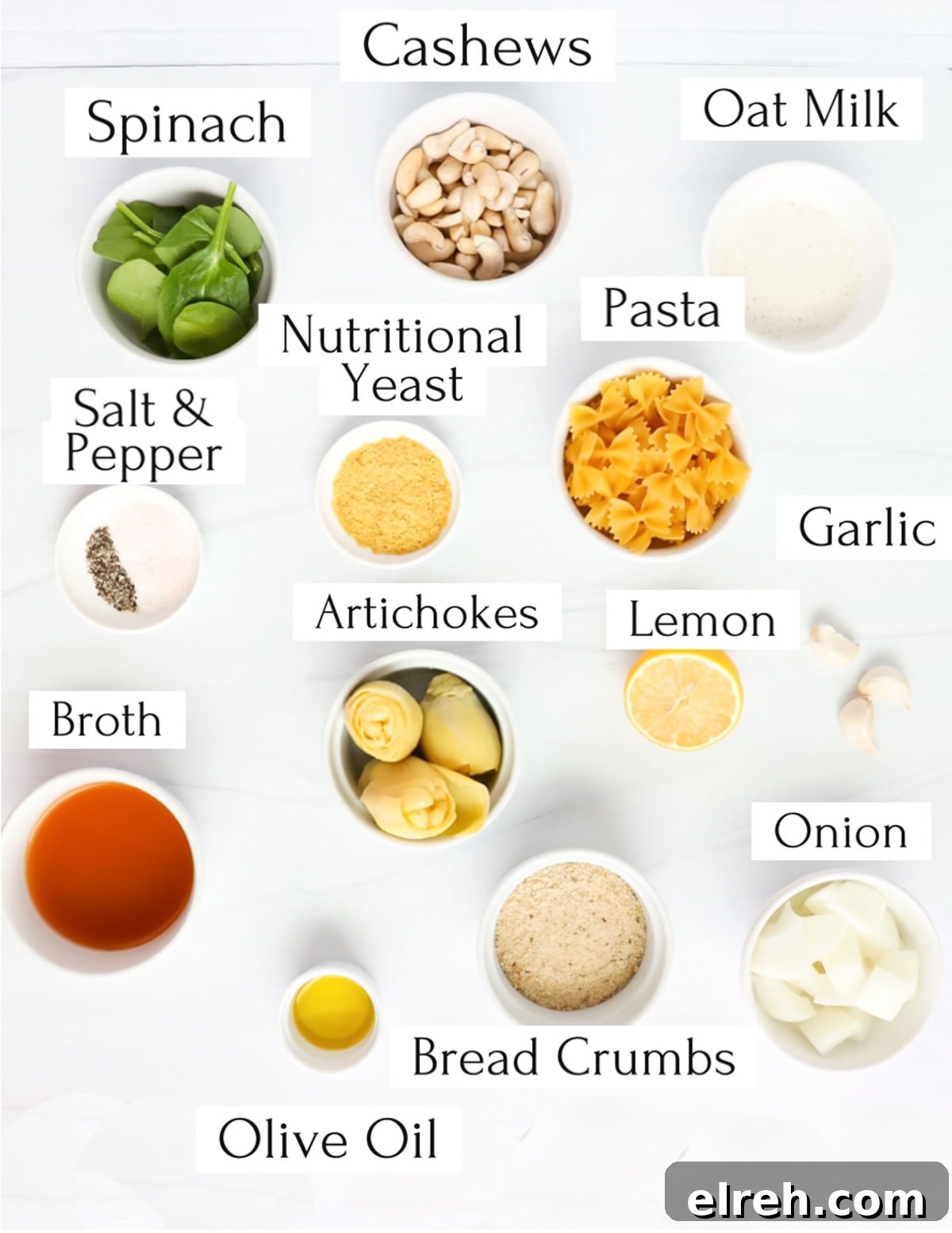 Labeled ingredients in white bowls including: cashews, spinach, oat milk, nutritional yeast, pasta, salt and pepper, artichokes, lemon, garlic, onion, broth, olive oil, bread crumbs, onion.