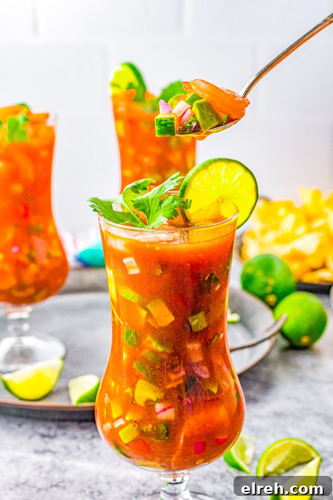 Authentic Mexican Shrimp Cocktail Recipe 5 A spoon lifting a bite from a glass of Mexican shrimp cocktail.