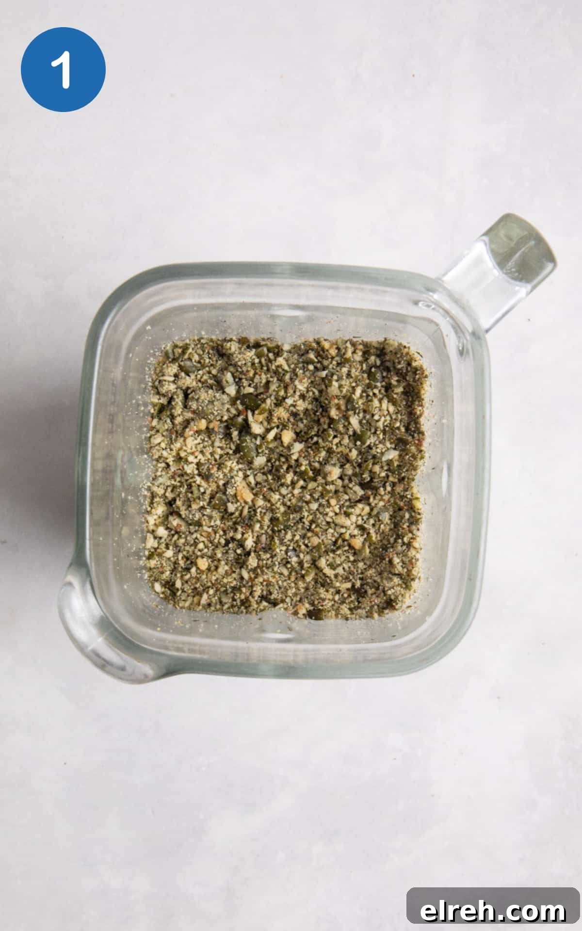 Gluten-Free Seeded Loaf Recipe with Flax, Sunflower and Chia 4 blended seeds in food processor on white surface.