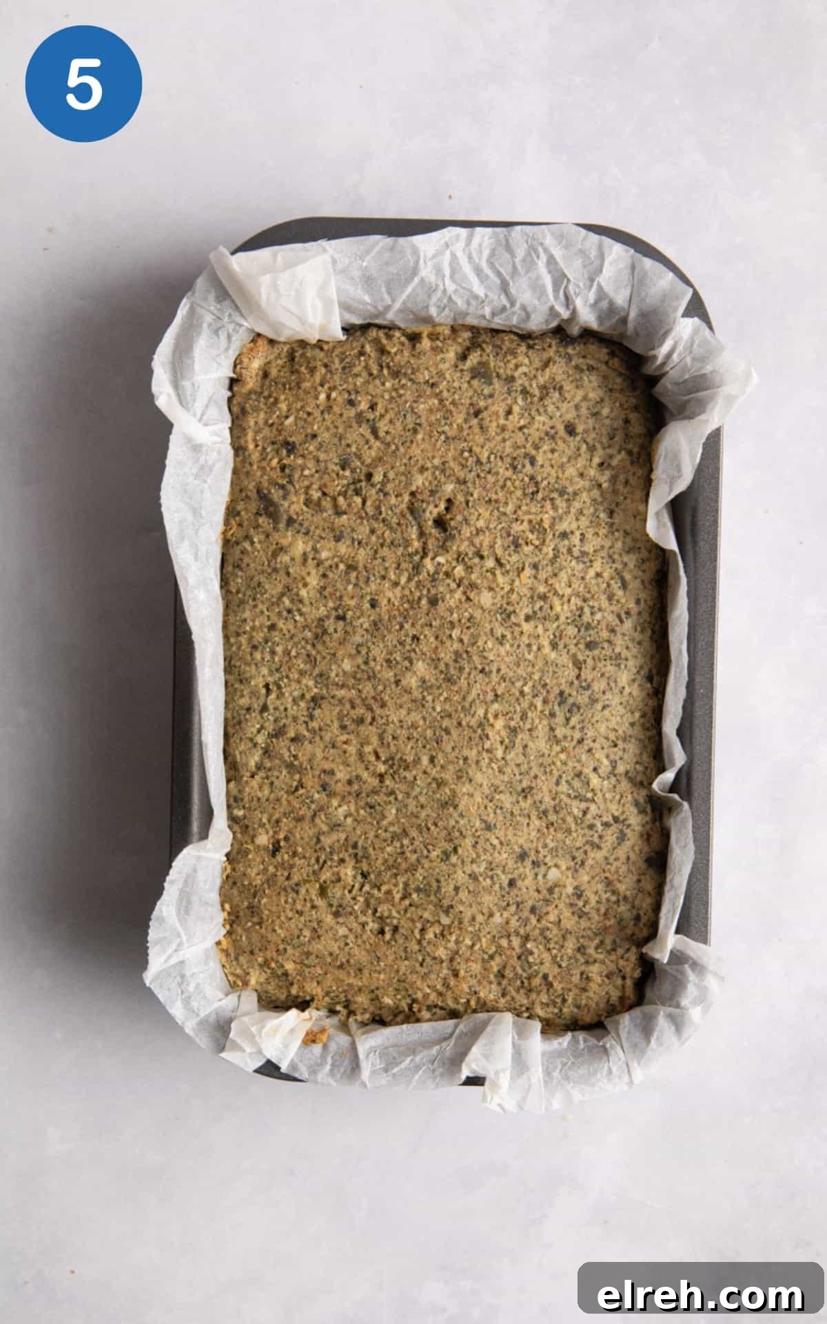 Gluten-Free Seeded Loaf Recipe with Flax, Sunflower and Chia 8 Gluten Free seeded loaf in break loaf tin with parchment paper on white surface.