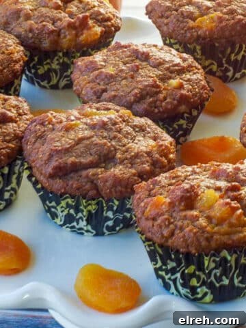 healthy bran pumpkin muffins on a white cake platter with dried apricots