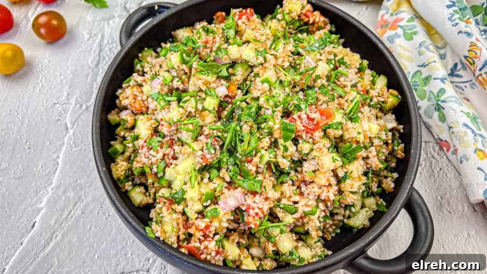 A black bowl filled with tabbouleh salad with smoked tomatoes.