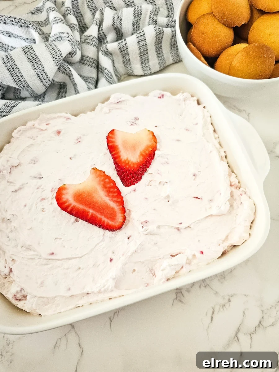 No-Bake Strawberry Cheesecake Dip Recipe 2 Strawberry cheesecake salad in a white bowl with Nilla wafers on the side for dipping.