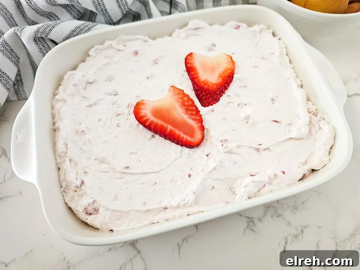 No-Bake Strawberry Cheesecake Dip Recipe 3 Strawberry cheesecake salad in a white bowl with Nilla wafers on the side for dipping.