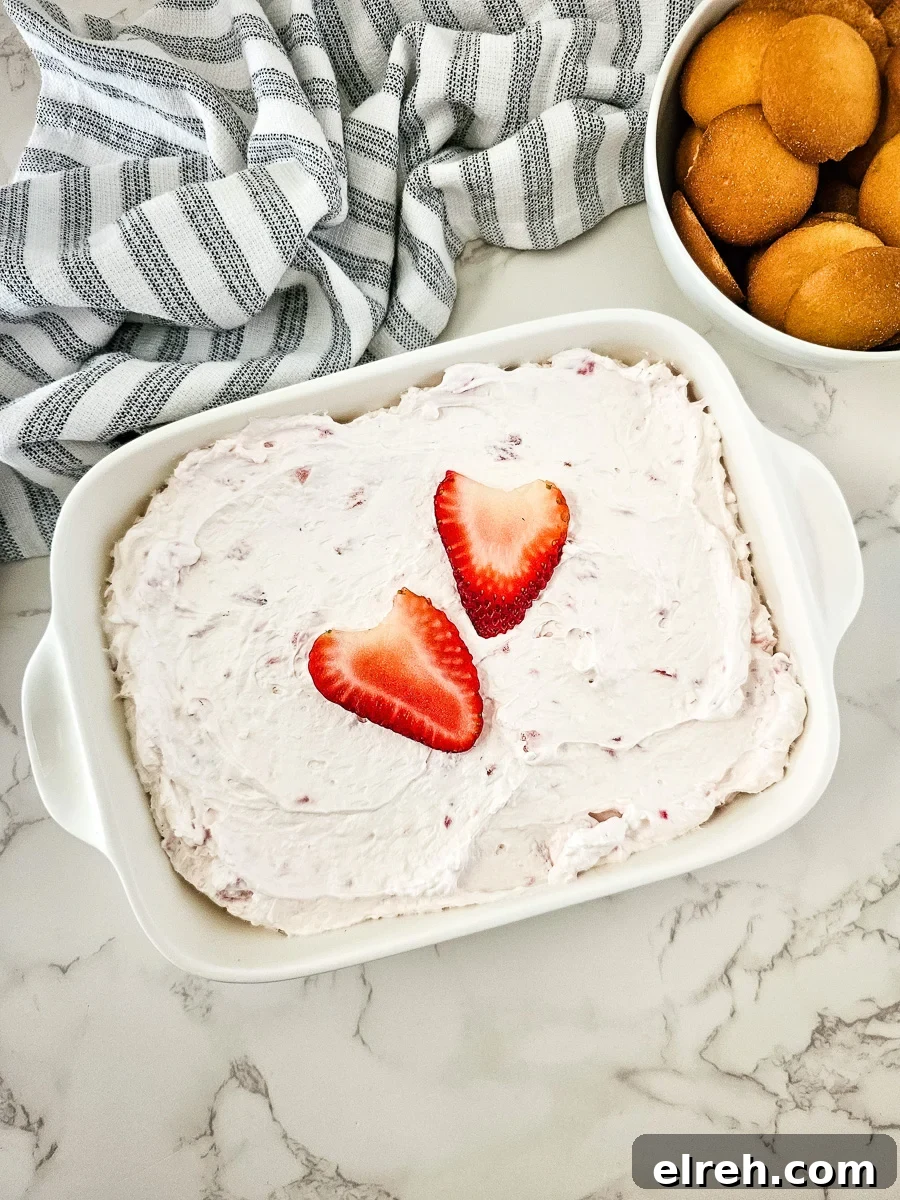No-Bake Strawberry Cheesecake Dip Recipe 7 Strawberry cheesecake salad in a white bowl with Nilla wafers on the side for dipping.