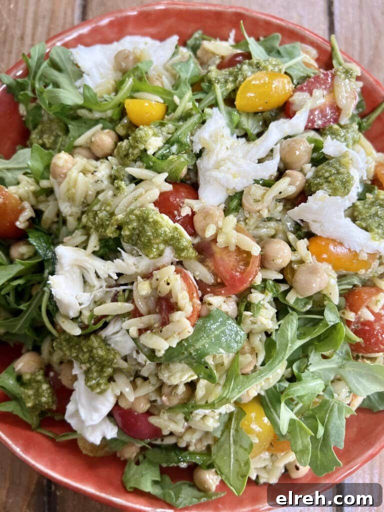 Orzo pesto salad in orange bowl.