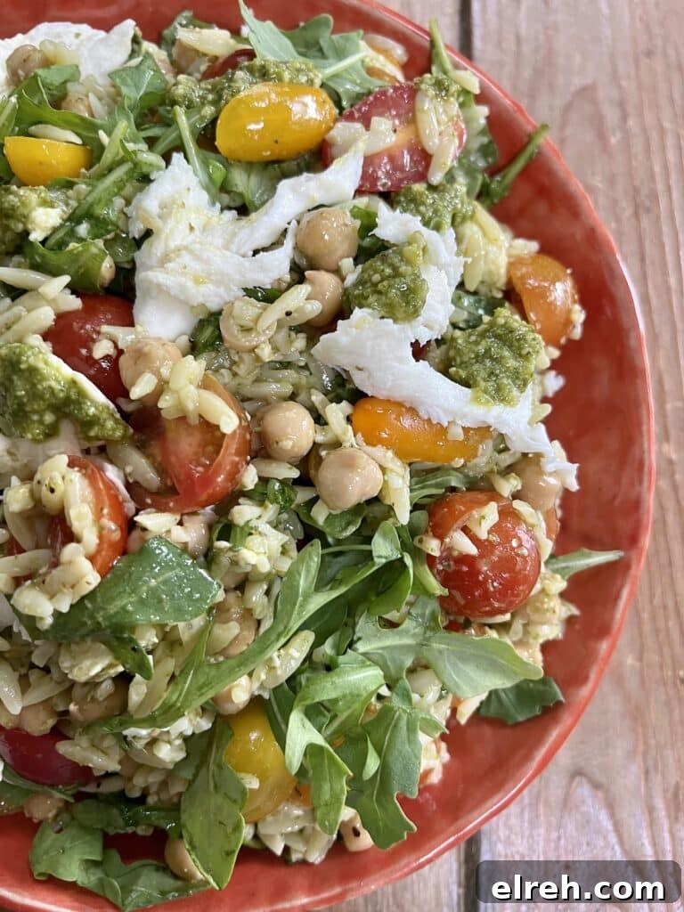 Orzo pasta salad in orange bowl.