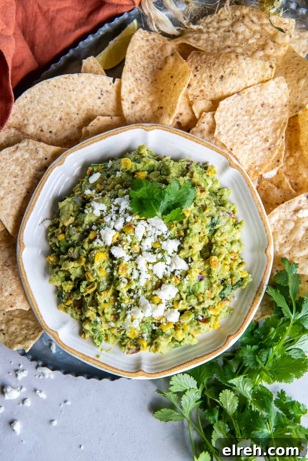 Charred Corn Guacamole Recipe with Lime and Cilantro 9 A top down shot of a bowl of corn guacamole surrounded by tortilla chips.