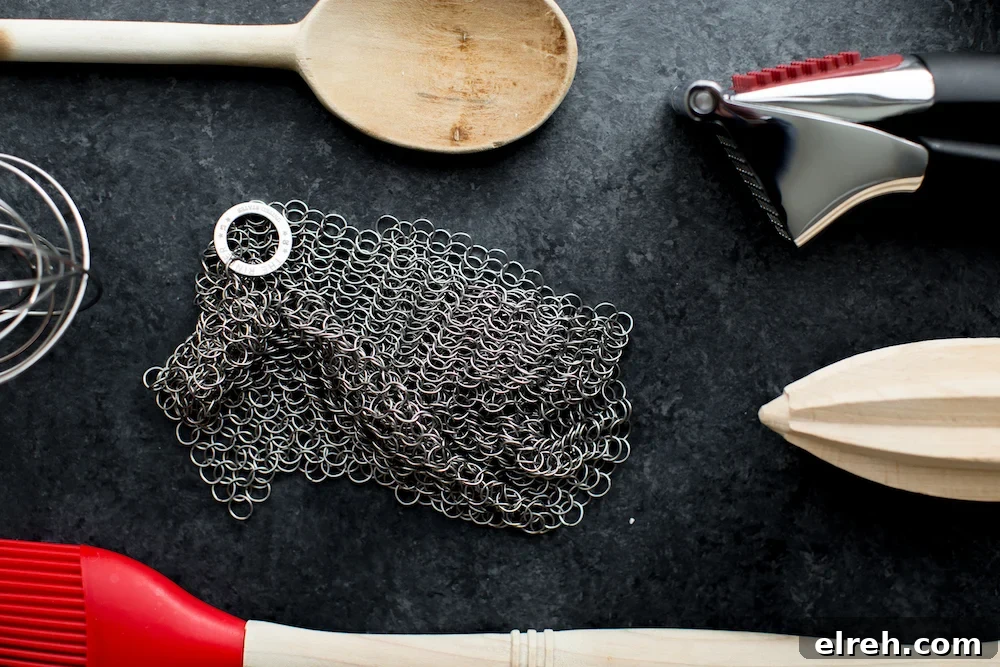 kitchen tools including garlic press, citrus reamer, wooden spoon, and chainmail scrubber