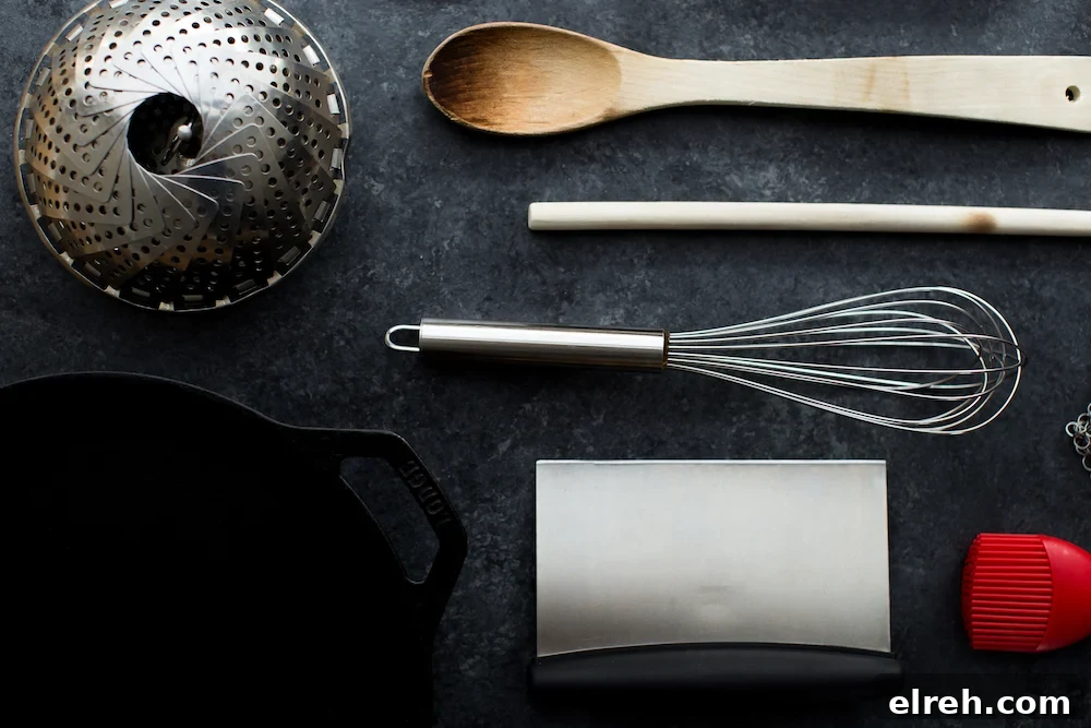 kitchen tools including whisk, steamer, wooden spoon, bench scraper and cast iron skillet
