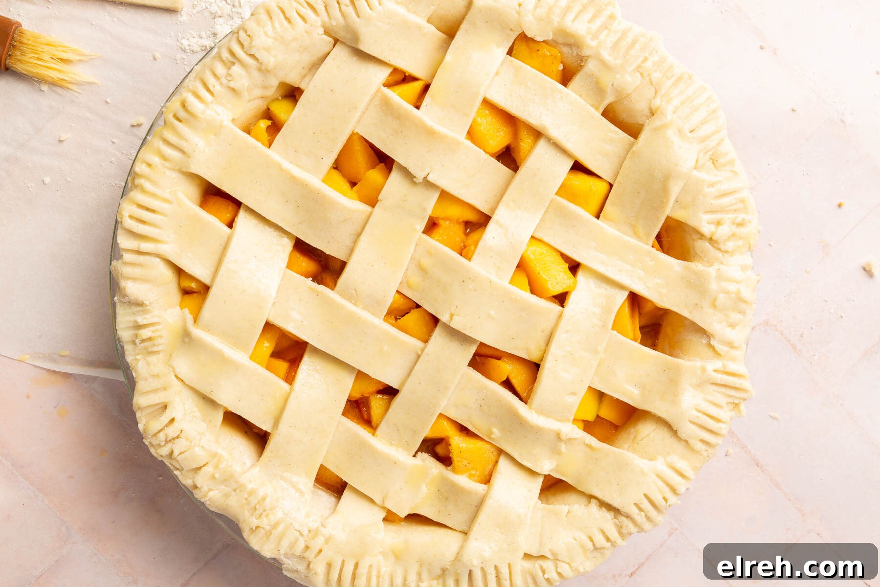 Gluten-Free Peach Mango Pie Recipe 13 An unbaked gluten-free peach mango pie with a lattice crust brushed with egg wash before baking.
