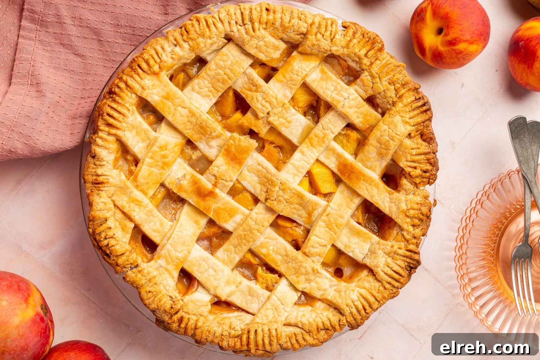 Gluten-Free Peach Mango Pie Recipe 14 An overhead view of a gluten-free peach mango pie with a lattice crust and fresh peaches around it.